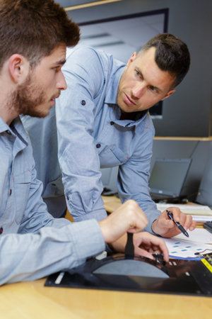 two men in the office with checklist
