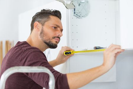mature man using a spirit level in his kitchenの写真素材