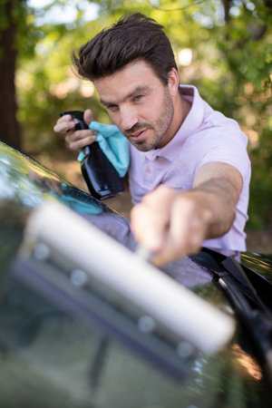 happy man cleaning his car window