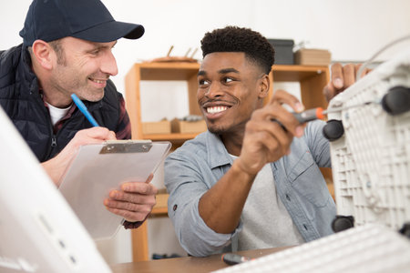 a male technician repairing a printer with teacherの写真素材