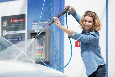 woman washes a car with a hoseの写真素材