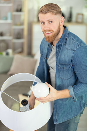 man changing compact-fluorescent cfl bulbsの写真素材