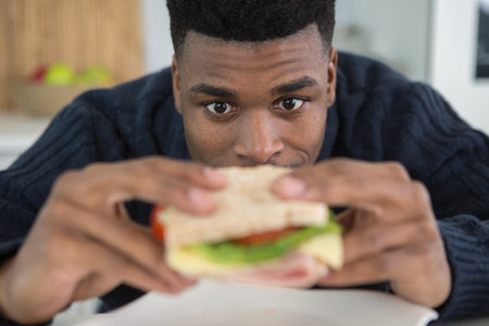 young guy has lunch eating sandwichの写真素材