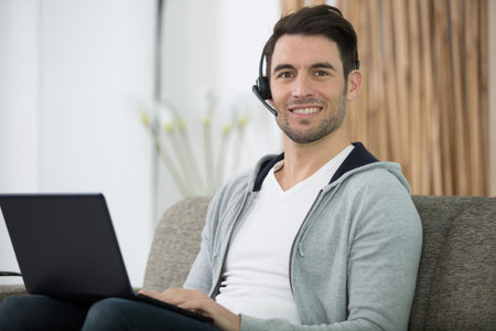 man in headset working with laptop from home