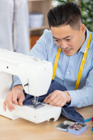 young man tailor working on new clothing