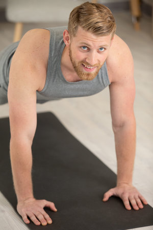 smiling man doing push-ups in the gym or at homeの写真素材