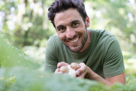 cheerful man gathering mushrooms in the woodsの写真素材