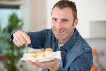 man preparing tapas for visitors at homeの写真素材