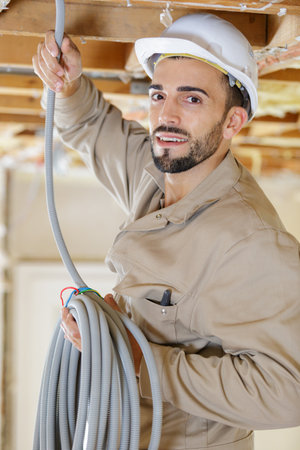 portrait of tradesman holding reel of cableの写真素材