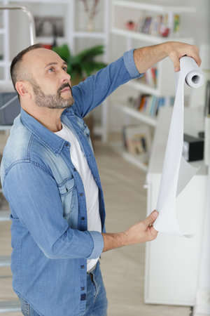 man wallpapering his new flat