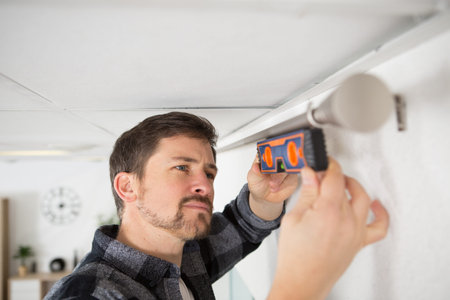 man checking curtain rail with spirit level