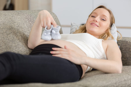pregnant woman holding small unborn baby shoes