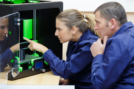 portrait of man and woman pointing at 3d printer