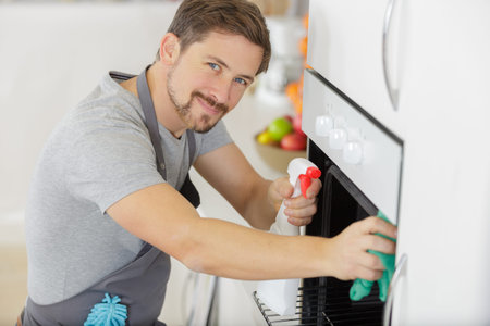 man with cloth cleaning inside oven at home kitchen