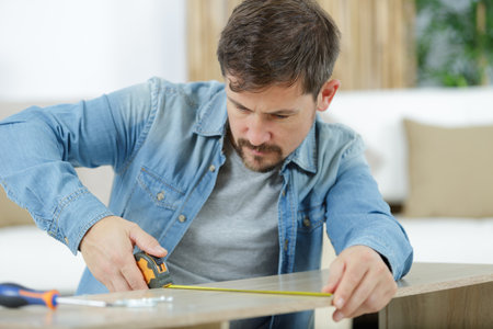 a man worker in the carpenter workroom renovation using tapeの写真素材