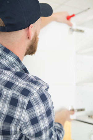 man posing while fixing cupboard hingesの写真素材