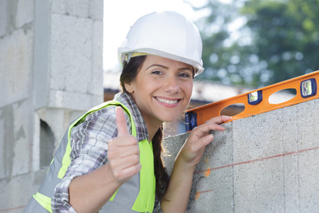 female construction worker with thumbs up holding level