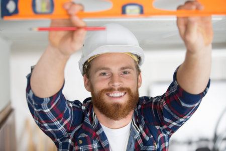 happy man taking measures with spirit level