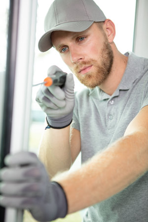 service man installing window using screwdriver