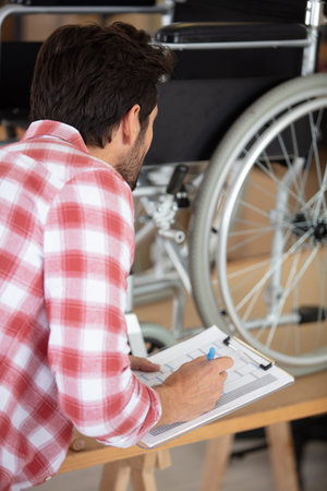 young man repairing wheelchair in his officeの写真素材