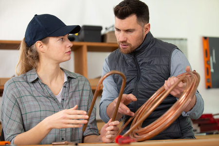 man and woman working on cooper pipes of gas