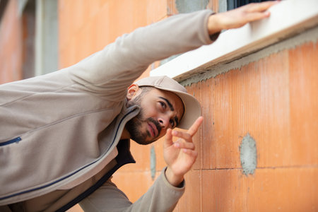 builder checking brick wall with spirit level