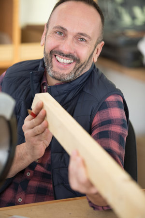 portrait of handsome smiling carpenter with wood materialの写真素材