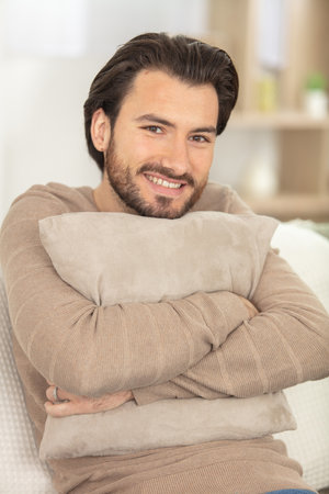 vertical shot of a young man hugging a pillowの写真素材