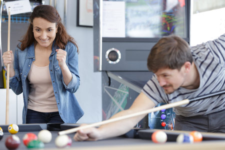 young couple playing snooker together in bar