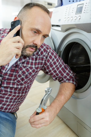 man on the phone next to washing machineの写真素材