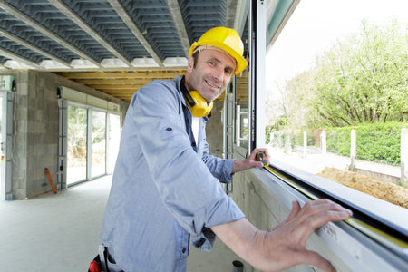handsome man installing bay window in a construction site