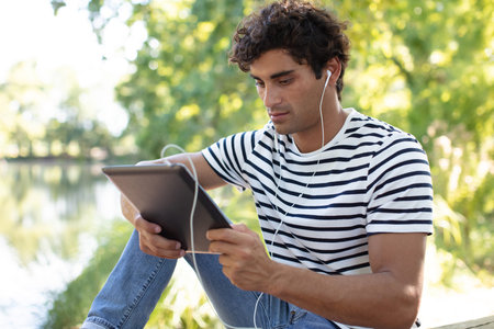 man sitting near a lake with digital tablet