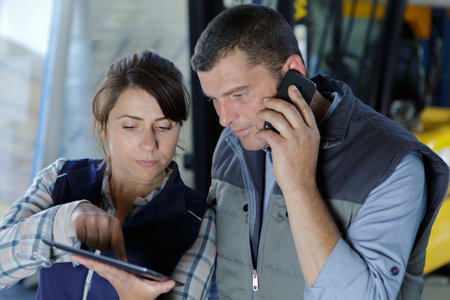 warehouse workers looking at tablet and using smartphone