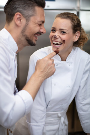 man and woman having fun with chocolate in icecream factoryの写真素材