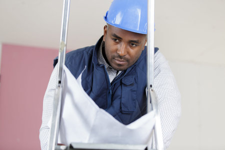 male builder on ladder reading