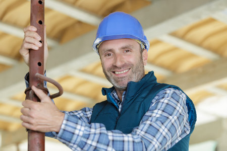 happy builder holding copper pipes