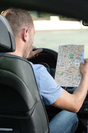 man holds a map in his car