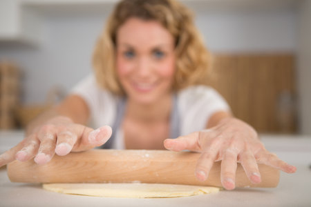 woman is rolling dough with rolling pinの写真素材