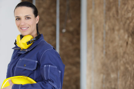 female construction worker wearing yellow helmet and protective headphones
