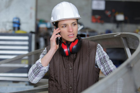 female worker speaking on mobile phone in an industrial areaの写真素材