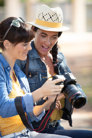 two happy friends with cameras outdoorsの写真素材