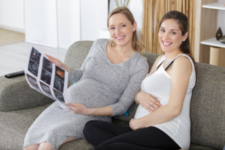 two pregnant women sitting on sofaの写真素材