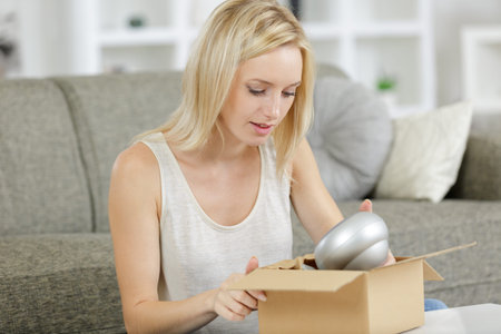 woman at home unpacking item from cardboard box