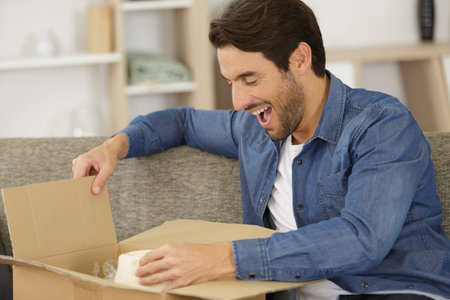 happy man opening parcel box at homeの写真素材