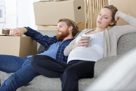 young pregnant couple sitting on sofaの写真素材