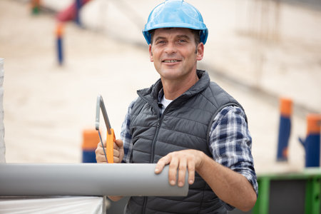 carpenter cutting pipes on building site