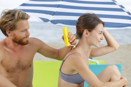 man applying suncream to his girlfriends backの写真素材