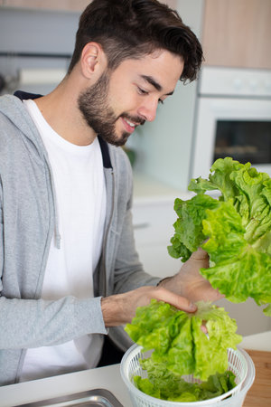 a sporty man is preparing a salad in the kitchenの写真素材