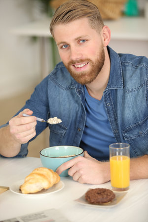 portrait of happy young man having healthy breakfastの写真素材