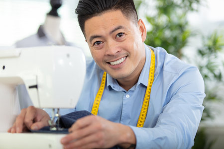 handsome fashion designer sewing with a sewing machineの写真素材